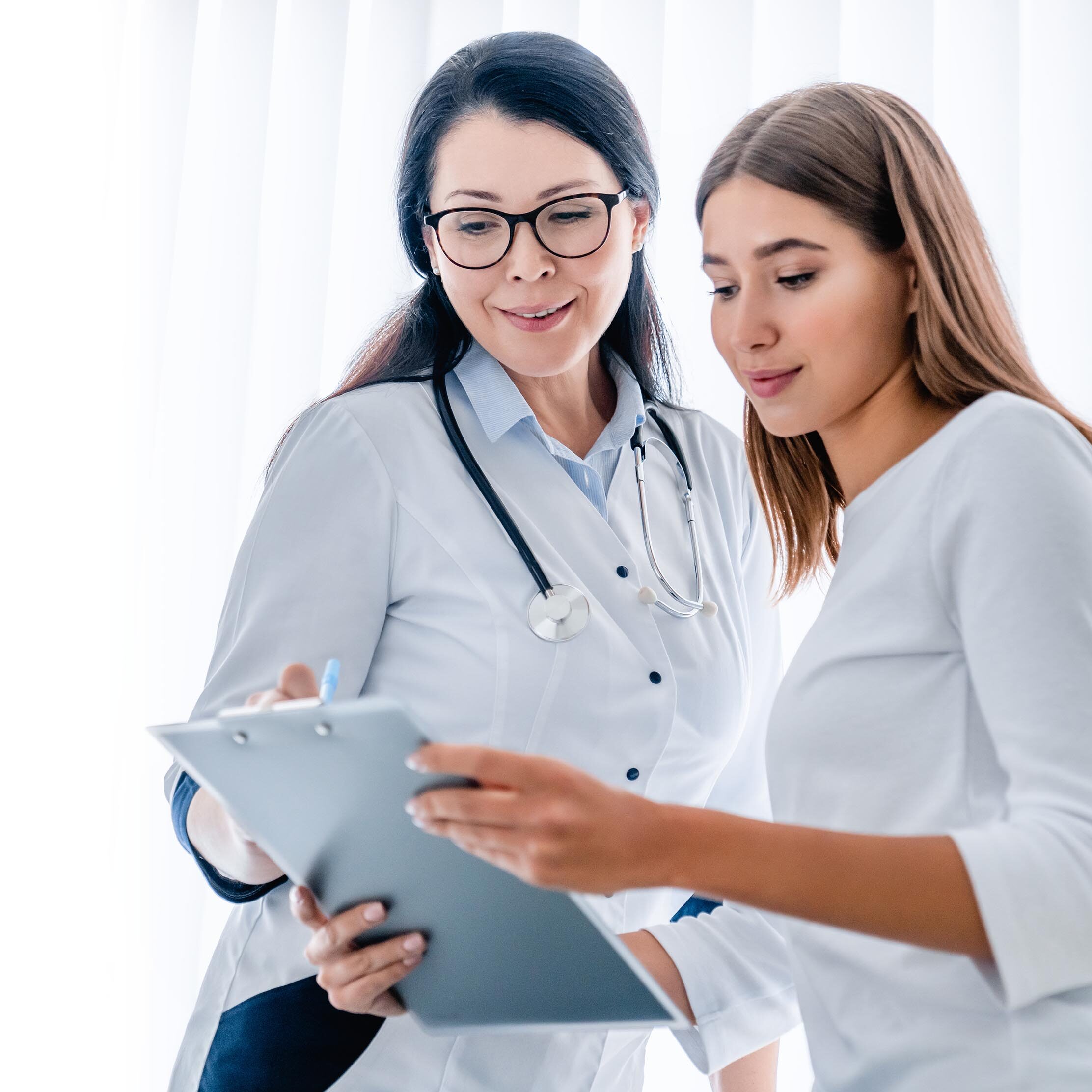 Woman doctor and her patient looking at tablet together and discussing how to Become a Verified Retailer